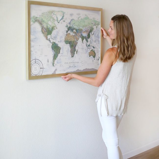woman in white tank top and white pants standing in front of map